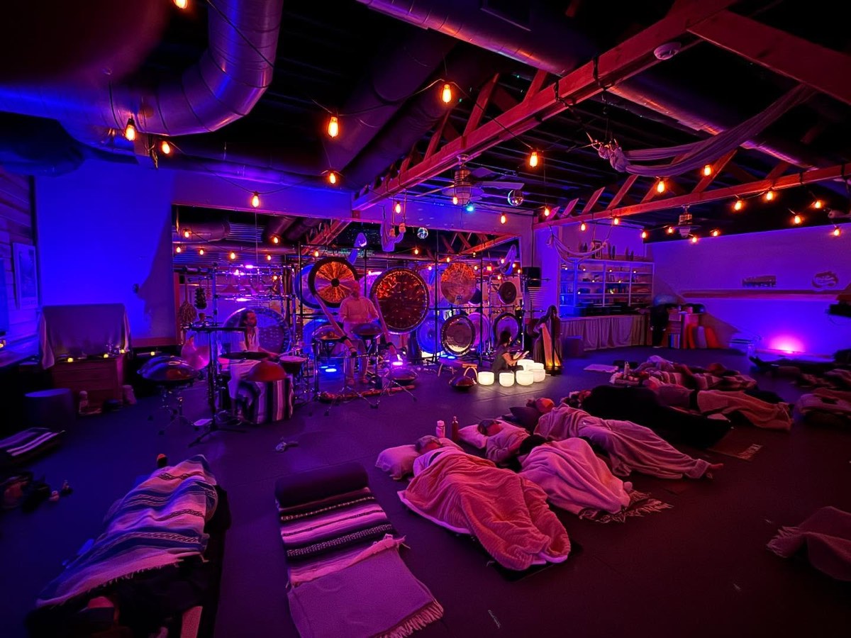 A sound bath at Renegade Yoga: the main room in low light, gongs at the front, students lying under blankets